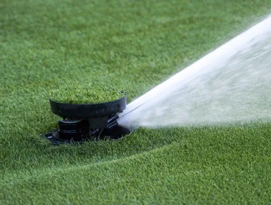 Close up of an irrigation sprinkler in action on a sportsfield