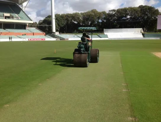 Machine and technician proof rolling the natural turf on a stadium sports field