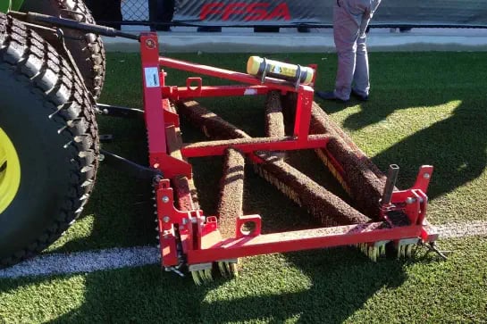 Close up on the machinery used on maintenance tractor to maintain synthetic turf