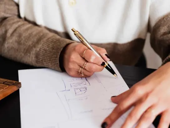Woman holding a pen and designing a plan on a white paper