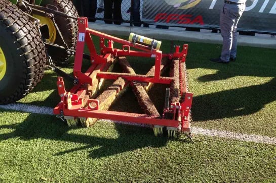 Maintenance machine being used on hockey synthetic turf sports field