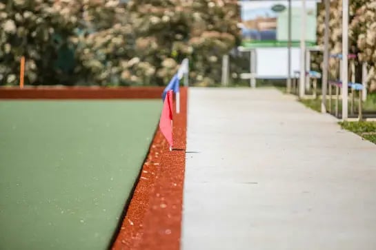 Blue and red flags on the side of a lawn bowls field of play