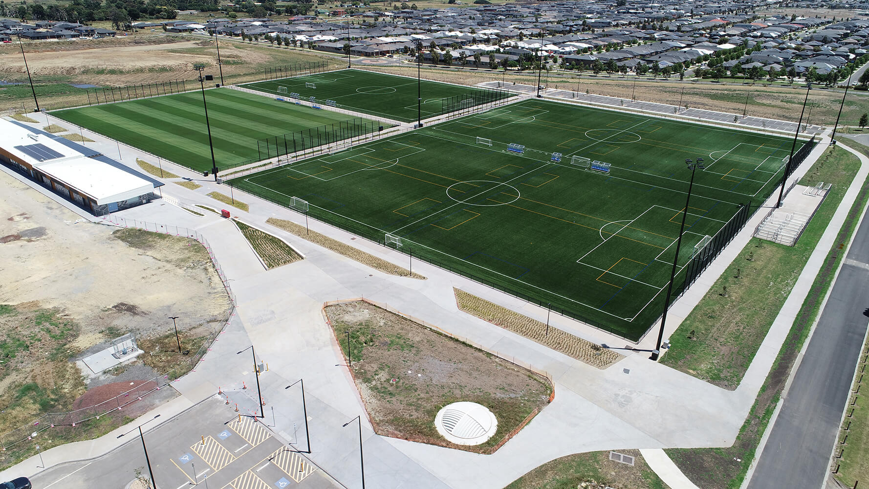 Aerial view of three FIFA Compliant synthetic turf pitches and an elite natural turf hybrid pitch surface in a suburban area