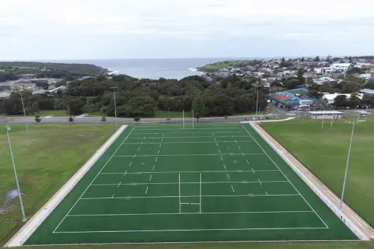 Aerial view of an outdoor natural turf rugy Field of Play with ocean in the background