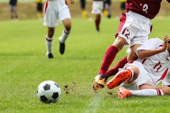 Close up of players legs trying to shoot in soccer ball on a natural turf soccer sports field