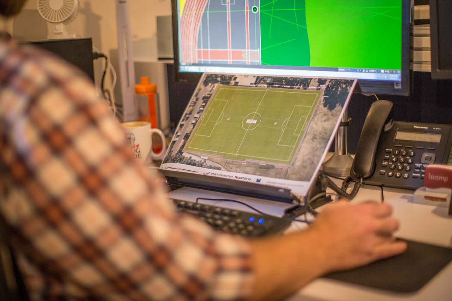 Close up of a civil engineer sitting at his desk working on a 3D drawing of a sportsfield on his computer