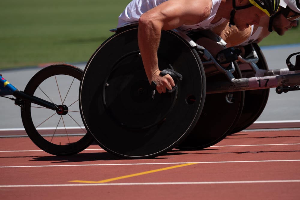 Athlete in a wheelchair racing competing in a race on a red outdoor athletic track