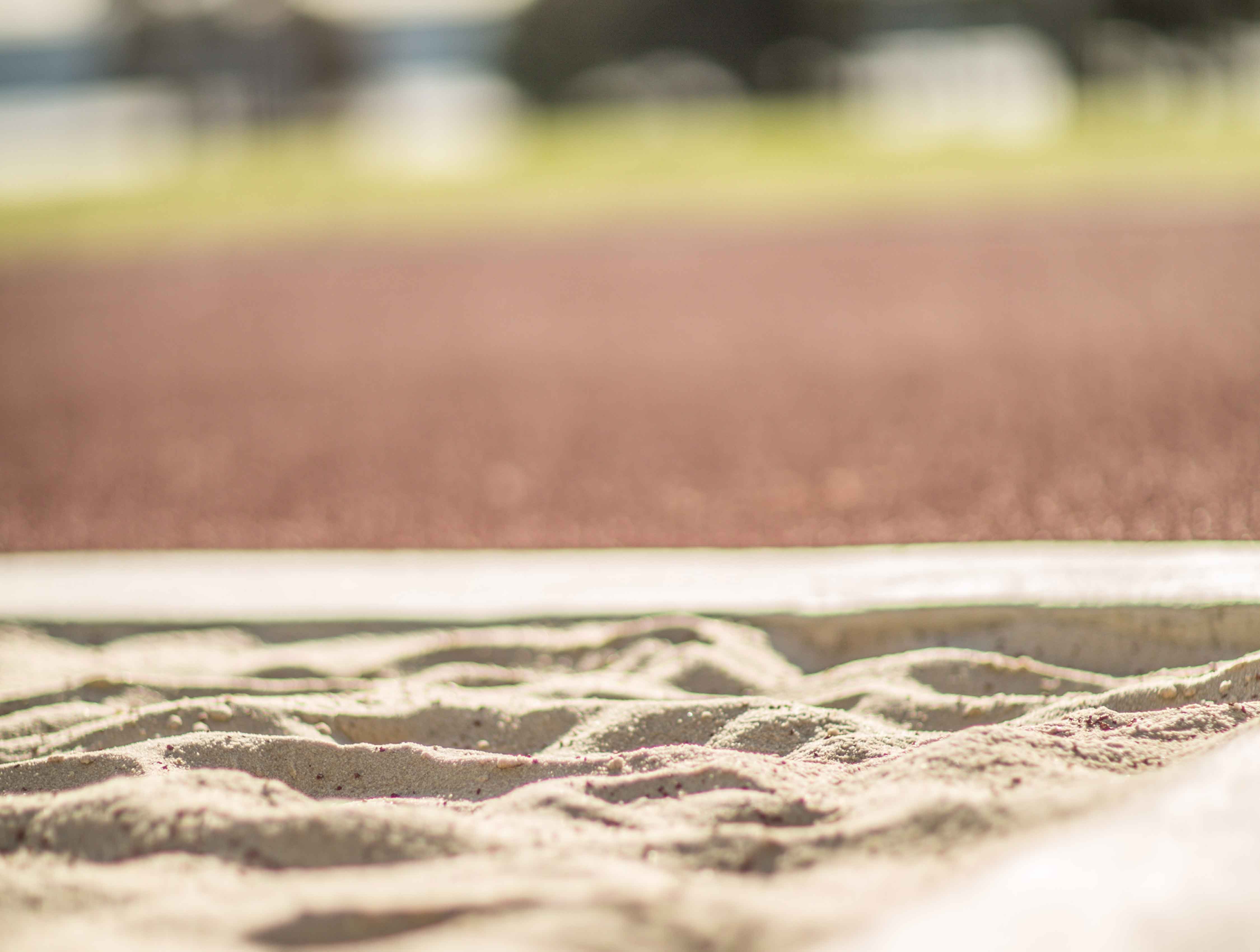 Close up of a sand pool next to an outdoor athletic running track