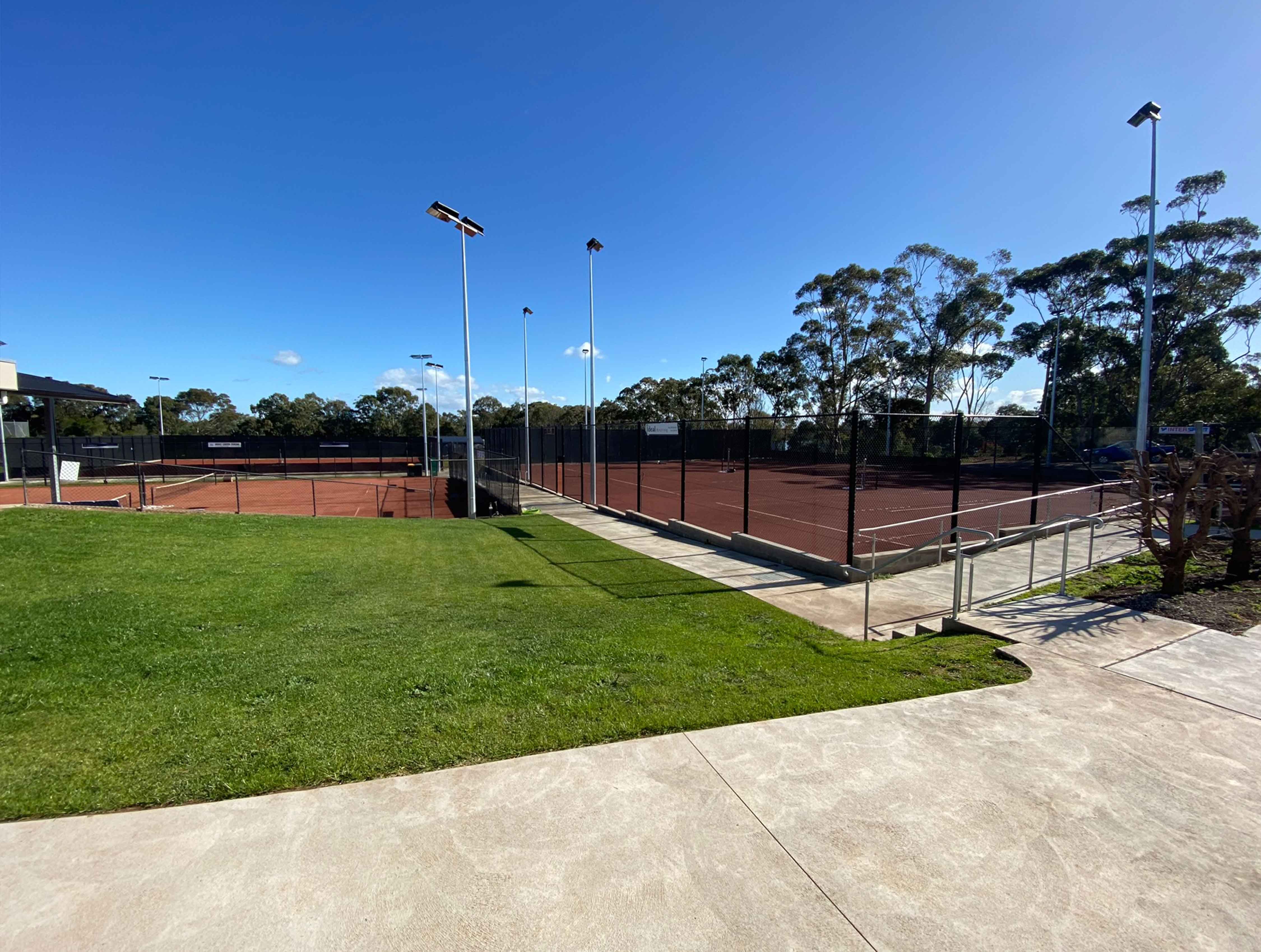 Panoramic view of an outdoor red porous tennis court surface with white line markings