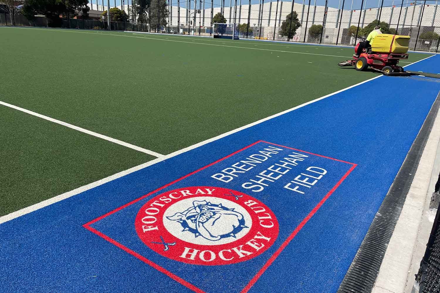 Green and blue synthetic turf surface for an outdoor hockey field with the team logo on it