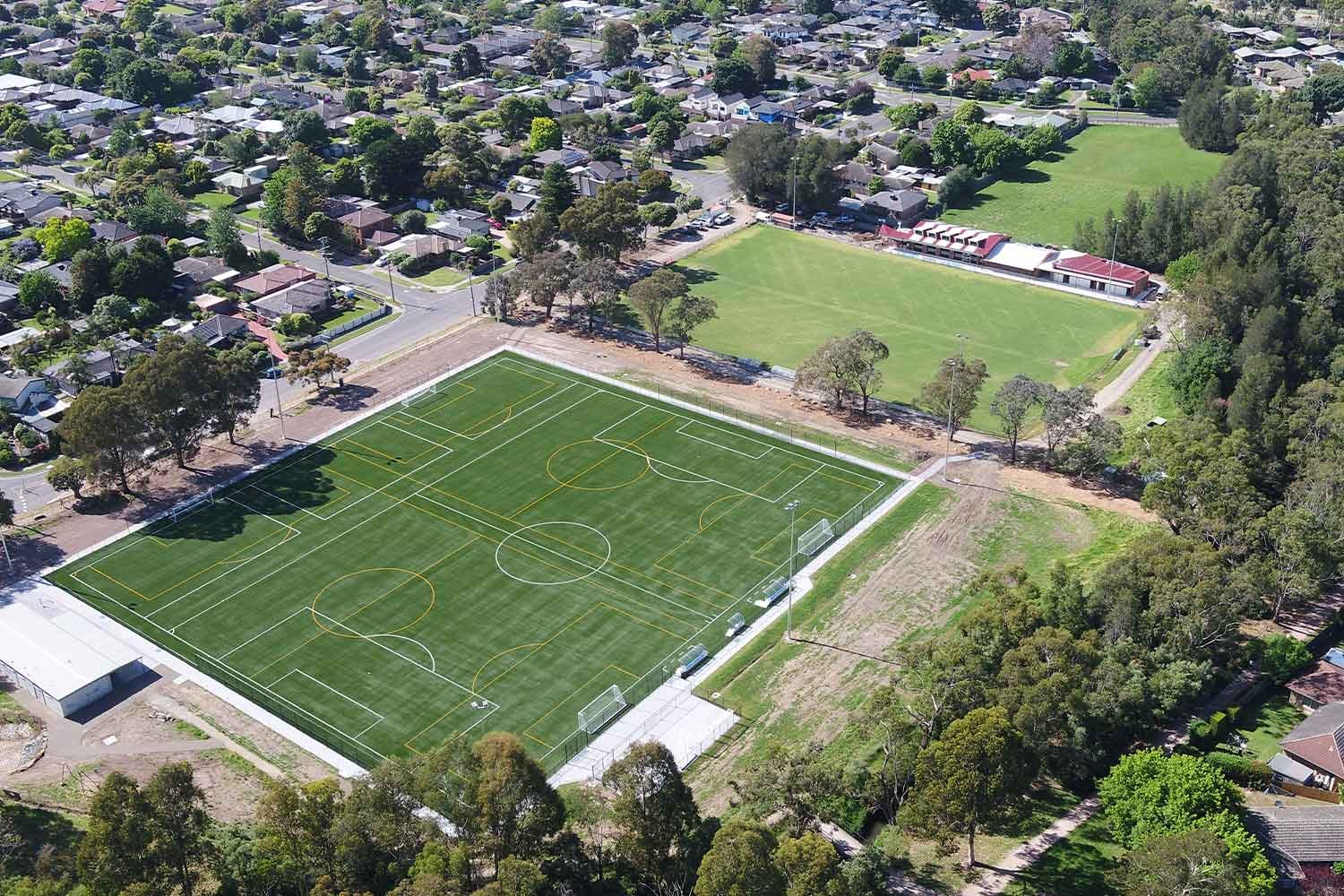 Aerial view of an outdoor soccer sports field with a synthetic turf surface and white and yellow line markings