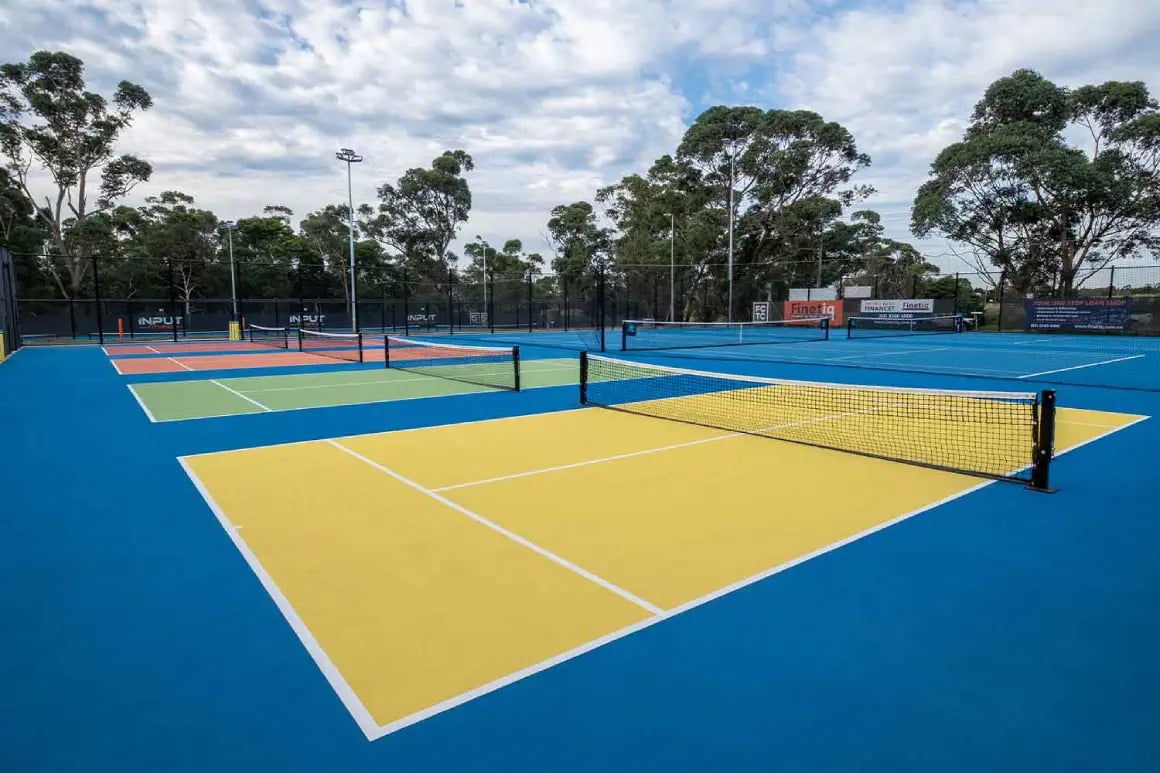 Panoramic view of outdoor tennis courts with bright yellow, blue, green, red colours